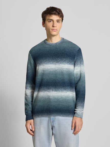 Männermodel trägt Regular Fit Strickpullover mit Baumwoll-Anteil Modell 'BERTIL' von Only & Sons, Allover-Muster in Blautönen, Ganzkörperansicht von vorne.