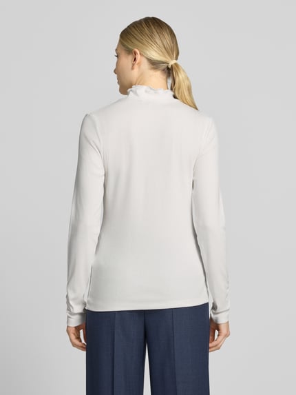 Frauenmodel trägt Slim Fit Longsleeve aus Baumwoll-Mix von MORE & MORE in Weiß mit Strukturmuster und Stehkragen, Ganzkörperansicht Rückansicht. Rückenlänge bei Größe 36: 58 cm, elastischer Stoff.