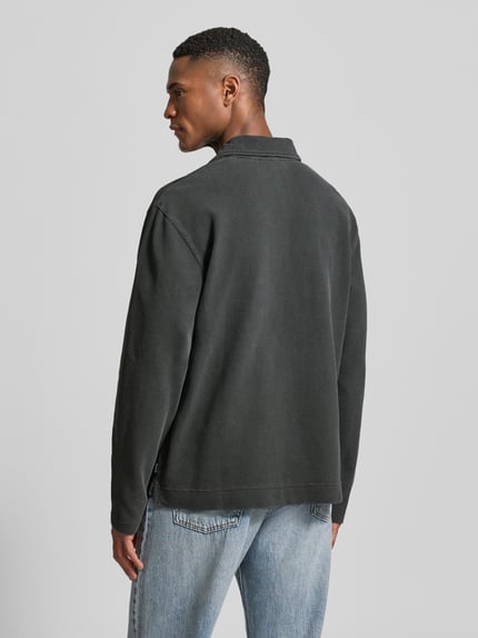 Männermodel trägt Loose Fit Poloshirt aus Baumwolle Modell 'Thiago' von Wood Wood, dunkles Grau, strukturierte Oberfläche, Rückenansicht.