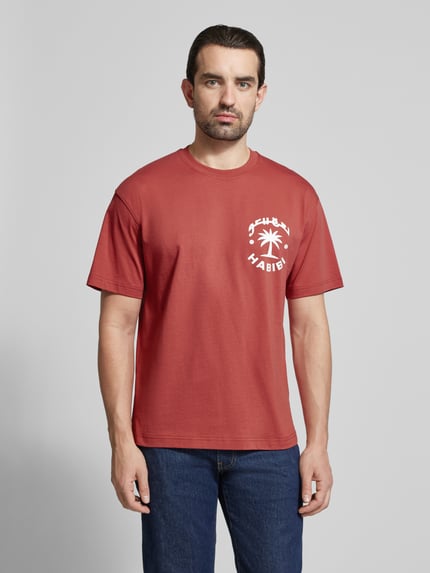 Männermodel trägt Regular Fit T-Shirt aus reiner Baumwolle Modell 'KARAN' von Strellson, unifarben, Schriftzug-Print, Ganzkörperansicht von vorne.