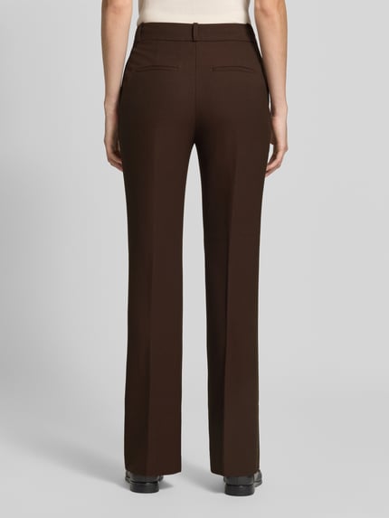 Modelka nosi Slim Fit Schmale Hose mit Viskose-Anteil od GANT, jednolity kolor brązowy, splot twill, wpuszczane kieszenie, Kanty, widok całej sylwetki z tyłu