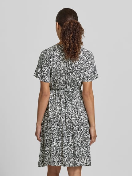 Frauenmodel trägt Minikleid aus Viskose mit V-Ausschnitt und Knopfleiste von Zero, schwarz-weißes Allover-Muster, A-Linie, Ganzkörperansicht Rückansicht