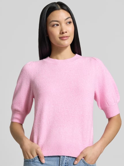 Frauenmodel trägt Regular Fit Pullover mit Puffärmeln von VERO MODA in Hellrosa, weiche Struktur, Nahaufnahme Oberkörper.