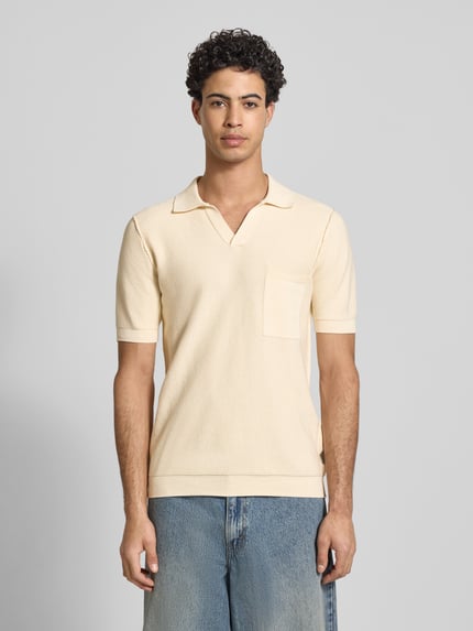 Männermodel trägt Slim Fit Poloshirt in Strick-Optik von Replay, reine Baumwolle, V-Ausschnitt, Brusttasche, Hellgelb, Ganzkörperansicht von vorne.