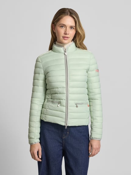 Frauenmodel trägt Steppjacke mit Reißverschlusstaschen Modell 'SISTER JUDY' von Frieda & Freddies in hellem Mintgrün, schlanker Schnitt, Stehkragen, silberfarbener Reißverschluss, Ganzkörperansicht von vorne.