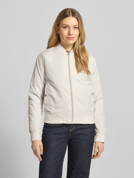 Vrouwenmodel draagt Regular Fit jack met opstaande kraag model 'Zaymi' van CARS JEANS, steekzakken, ritssluiting, elastische boorden, ruglengte bij maat S: 61 cm, schouderbreedte 41 cm, borstwijdte 39 cm, mouwlengte 60 cm, lichtbeige kleur, effen structuur. Volledige lichaamsaanzicht van voren.