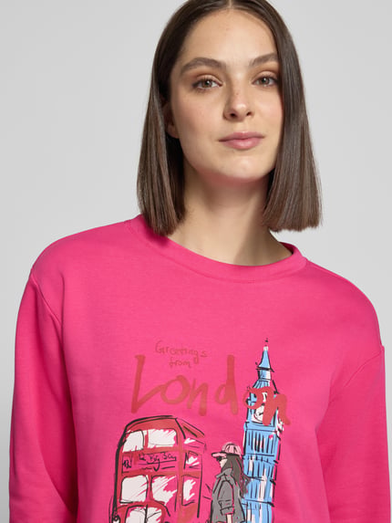 Frauenmodel trägt Sweatshirt mit Motiv-Print und Rundhalsausschnitt von Milano Italy, Baumwoll-Mix in Pink, Nahaufnahme Oberkörper.
