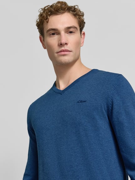 Männermodel trägt Pullover mit Logo-Detail von S.OLIVER CASUAL in Unifarbe Blau, Feinstrick, V-Ausschnitt, Nahaufnahme Oberkörper