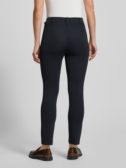 Vrouwenmodel draagt Stoffen broek in verkorte pasvorm Model 'Sydney' van Marc Cain, materiaalmix met stretch, recht model, labeldetail, knoop- en ritssluiting, bandwijdte maat 36: 37 cm, binnenbeenlengte: 70 cm, donkerblauw, gladde textuur, ganzkörperansicht achteraan.
