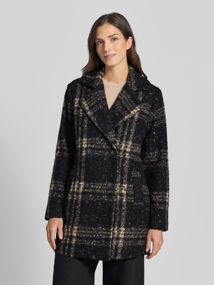 Frauenmodel trägt Mantel mit doppelreihiger Knopfleiste von SOYACONCEPT in mehrfarbiger Strickoptik mit kariertem Muster, Reverskragen, langen Ärmeln und seitlichen Eingrifftaschen, Ganzkörperansicht von vorne.