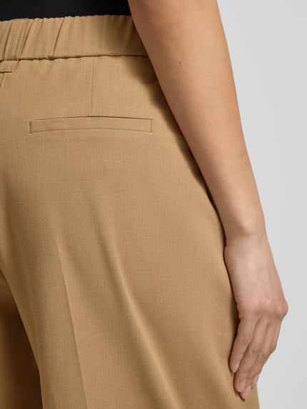 Frauenmodel trägt Barrel Fit Hose Modell 'Moira Bloom' von OPUS PANTS in Beige, Baumwoll-Mix mit Bügelfalten, Nahaufnahme Rückansicht.