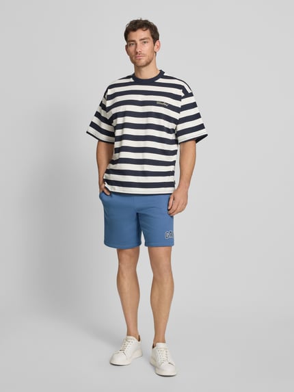Männermodel trägt Sweatshorts mit Logo und elastischem Bund von GAP aus Baumwoll-Mix in Blau, mit Eingrifftaschen, Regular-Fit, Ganzkörperansicht von vorne.