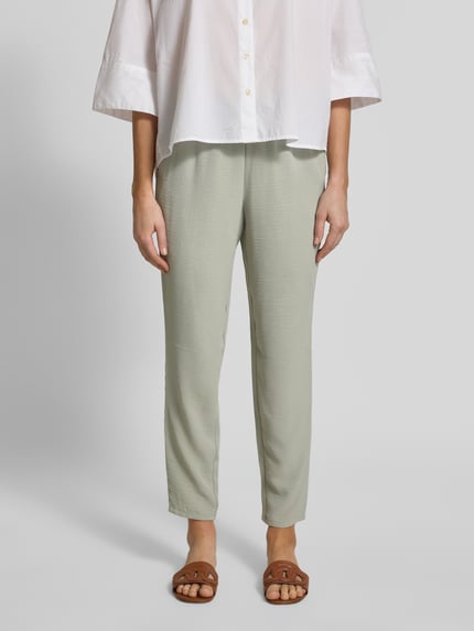 Frauenmodel trägt Jogpants mit elastischem Bund und Eingrifftaschen von Christian Berg Woman in hellem Grün, Slim Fit, Ganzkörperansicht von vorne.