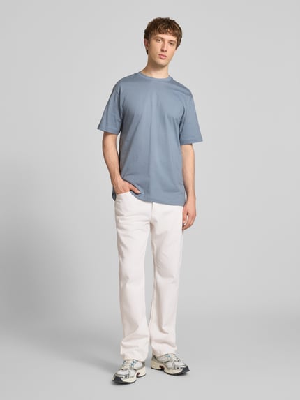 Męski model nosi Straight Fit Jeans aus reiner Baumwolle Modell 'EDGE' von Only & Sons, jednolity, 5-kieszeniowy twill, z metką, zapięcie na guziki, szerokie szlufki, biała tkanina, widok całej sylwetki z przodu.