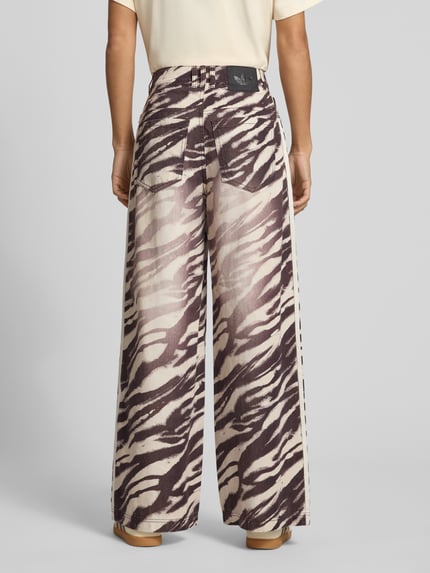 Frauenmodel trägt Regular Fit Jeans Wide Fit mit Eingrifftaschen von adidas Originals mit Animal Print und Allover-Muster, Ganzkörperansicht Rückansicht.