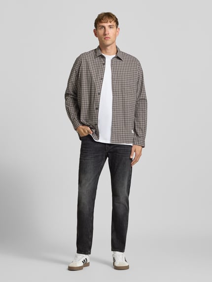 Männermodel trägt Regular Fit Straight Fit Jeans mit Label-Patch von JACK & JONES in Dark Wash Denim, Ganzkörperansicht von vorne.