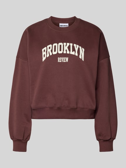 Produktfoto, Sweatshirt met labelprint en ronde hals van Review, dames katoenmix, relaxed fit, donkerbruin met witte letters.