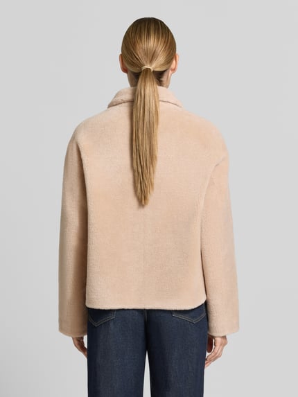 Frauenmodel trägt Regular Fit Jacke aus reiner Wolle von OAKWOOD in Beige mit Umlegekragen und aufgesetzten Taschen, Ganzkörperansicht Rückansicht.