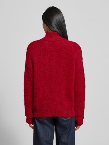Frauenmodel trägt Strickpullover mit Stehkragen und überschnittenen Schultern von Milano Italy in kräftigem Rot, Material-Mix mit Mohair-Anteil, Rückenlänge 57 cm, Ärmellänge 76 cm, Regular Fit, lockere Struktur, Ganzkörperansicht Rückansicht.