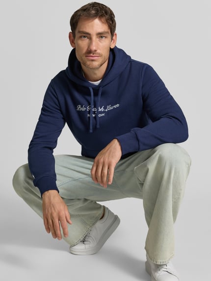 Männermodel trägt Relaxed Fit Hoodie aus katoenmix van Polo Ralph Lauren in donkerblauw, lichte broek, Ganzkörperansicht von vorne