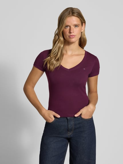 Frauenmodel trägt Slim Fit T-Shirt aus reiner Baumwolle von Tommy Jeans in Dunkellila, glatte Stoffstruktur, Damen T-Shirt, Nahaufnahme Oberkörper.