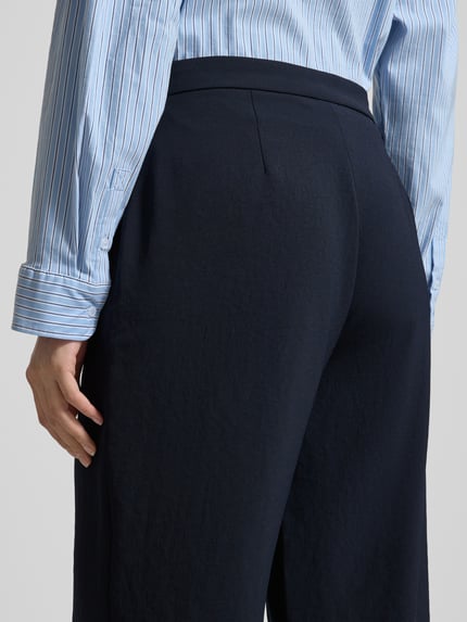 Frauenmodel trägt Hose mit Eingrifftaschen Modell 'PALINA 6/8' von Raffaello Rossi in Dunkelblau, strukturierte Oberfläche, Detailaufnahme Rückansicht, verkürzte Passform, Kontext: Damen Hose, Bundweite 40 cm, Innenbeinlänge 68 cm.