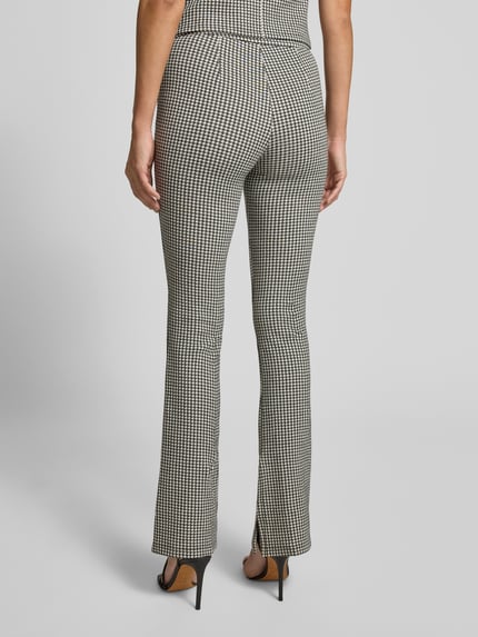 Frauenmodel trägt Slim Fit Schlaghose aus Baumwoll-Viskose-Mix Modell 'NAROSETTA' von HUGO mit Hahnentritt-Muster, Rückansicht Ganzkörperansicht.