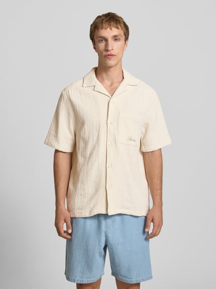 Männermodel trägt Regular Fit Freizeithemd mit Logo-Stitching von REVIEW in Beige, reine Baumwolle, Reverskragen, Halbarm, Ganzkörperansicht von vorne.