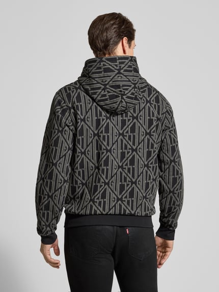 Männermodel trägt Hoodie im Allover-Look mit Känguru-Tasche van Guess, katoen, regular fit, zwarte en grijze tinten, rugaanzicht, Ganzkörperansicht Rückansicht.