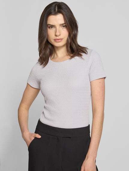 Frauenmodel trägt T-Shirt mit Label-Detail von Marc Cain, Damen T-Shirt, Elastischer-Material-Mix, Körpernaher-Schnitt, U-Ausschnitt, Rückenlänge bei Größe 36: 55 cm, helle Farbe, feine Struktur, schlichte Optik, Nahaufnahme Oberkörper.