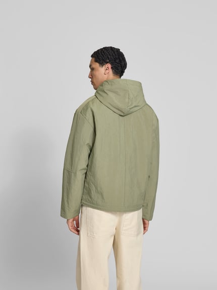 Männermodel trägt Regular Fit Jacke mit Kapuze von WON HUNDRED in Hellgrün, Känguru-Tasche, Reißverschluss, Tunnelzug, Rückansicht, Ganzkörperansicht. Rückenlänge 69 cm, Schulterbreite 56 cm, Ärmellänge 63 cm, Größe M.
