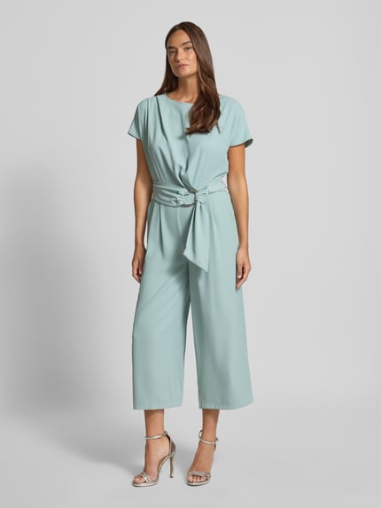 Frauenmodel trägt Jumpsuit mit Stretch-Anteil von Betty Barclay in Hellblau, elastischer Stoff, Gürtel, 7/8-Länge, Ganzkörperansicht von vorne.