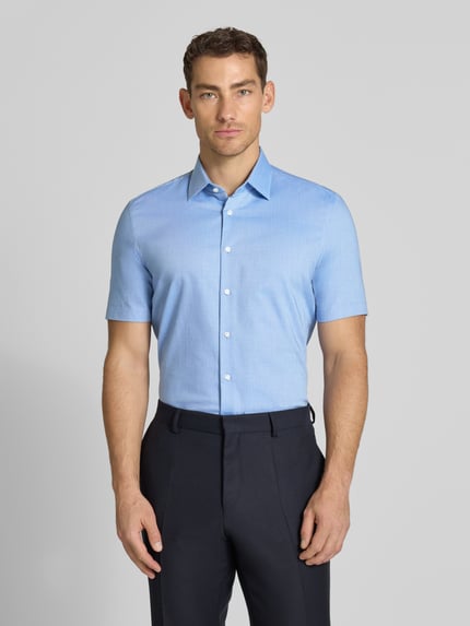 Männermodel trägt Slim Fit Business-Hemd mit Kentkragen von Jake*s aus Baumwoll-Mix in Hellblau, glatte Textur, Ganzkörperansicht von vorne.