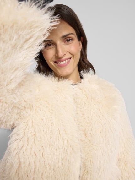 Vrouwenmodel draagt Jacke aus Kunstfell Modell 'Heti' van OPUS in crèmewit, zachte textuur, regular fit, close-up bovenlichaam.