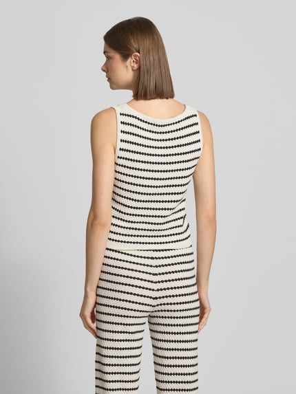 Frauenmodel trägt Strickweste mit V-Ausschnitt und Knopfleiste von REVIEW, schwarz-weiß gestreift, Material-Mix, Ganzkörperansicht Rückansicht.