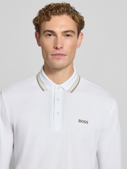 Männermodel trägt weißes Regular Fit Poloshirt aus reiner Baumwolle Modell 'Plisy' von BOSS, dezente Details, Nahaufnahme Oberkörper, Herren Poloshirt von BOSS.