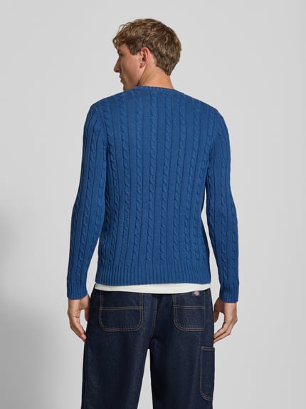 Männermodel trägt Strickpullover mit Zopfmuster und Rundhalsausschnitt von Superdry in Blau, reine Baumwolle, Rückansicht, Ganzkörperansicht.