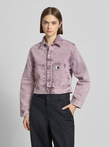 Kobiece modelka nosi Regular Fit Jeansjacke mit Logopatch Modell 'Arca' od Carhartt Work In Progress, bawełna, wpuszczane kieszenie, wykładany kołnierz, listwa guzikowa, długość tyłu w rozmiarze S 50 cm, szerokość ramion w rozmiarze S 41 cm, szerokość klatki piersiowej w rozmiarze S 51 cm, długość rękawów w rozmiarze S 61 cm, odcień fioletowy, proste kształty, tekstura denimowa, widok całej sylwetki od przodu.