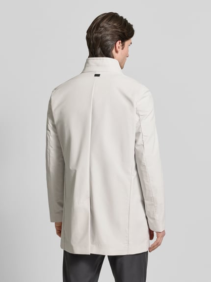 Männermodel trägt Regular Fit Mantel mit Stehkragen Modell 'FYNN' von Strellson in Unifarbe, Twilltextur, mit Schlitz und Label Patch, Ganzkörperansicht Rückansicht.