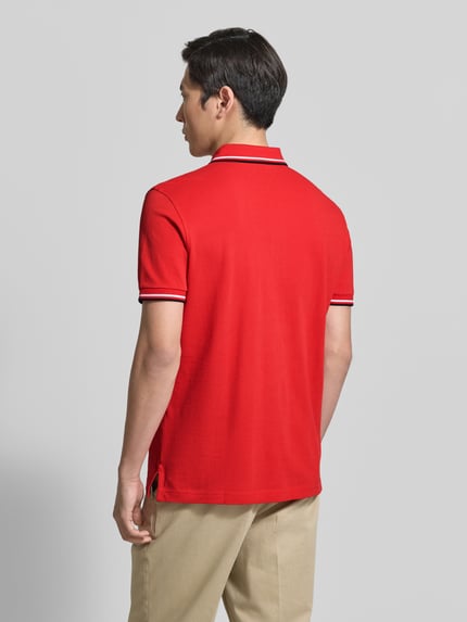 Mężczyzna nosi Regular Fit Poloshirt mit Kontraststreifen von Christian Berg Men, czerwona bawełna, widok całej sylwetki od tyłu.