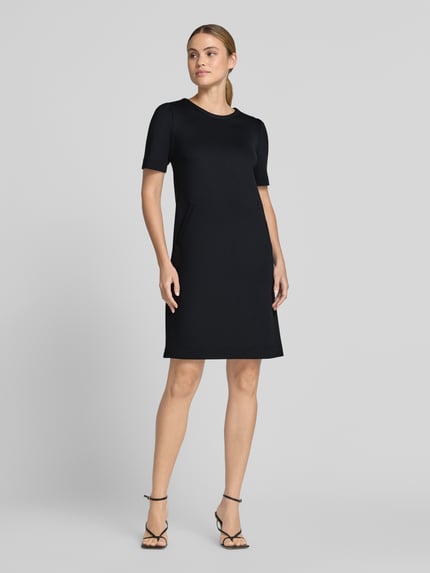 Vrouwenmodel draagt Knielanges Kleid met seitlichen Eingrifftaschen van Marc Cain, zwart, materiaalmix met stretch, A-lijn, ronde hals, ritssluiting, knielengte, steekzakken, ruglengte maat 36: 87 cm, borstwijdte maat 36: 43 cm, mouwlengte maat 36: 26 cm, volledige lichaamsopname voorkant.