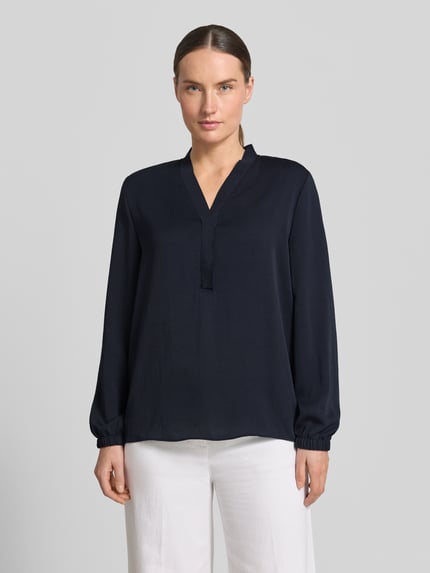 Frauenmodel trägt Bluse mit V-Ausschnitt und Label-Detail von Marc Cain, Loose-Fit, elastische Ärmelabschlüsse, Dunkelblau, Ganzkörperansicht von vorne, Damen Bluse, Rückenlänge bei Größe 36: 46 cm, Ärmellänge bei Größe 36: 60 cm.