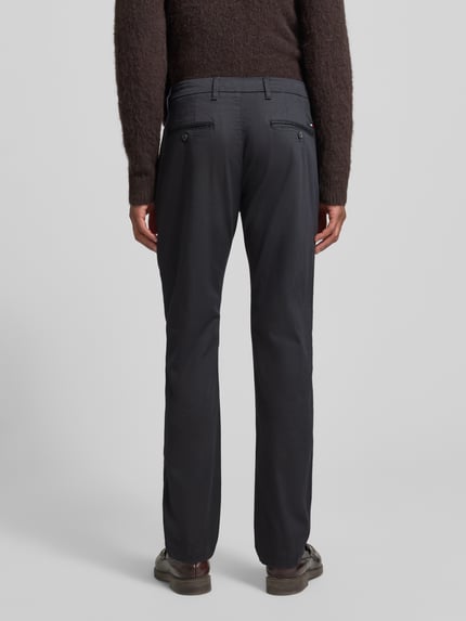 Männermodel draagt Regular Fit Chino uit katoenmix model 'DENTON' van Tommy Hilfiger met all-over motief, riemlussen, achterzakken, ganzebody-achteraanzicht.
