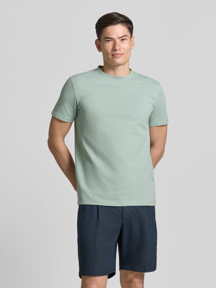 Mannenmodel draagt T-shirt met structuurpatroon en logo-stitching van Lerros, katoenmix met stretch, regular fit, ronde hals, ruglengte bij maat M 75 cm. Ganzkörperansicht von voren.