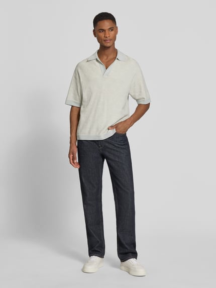 Männermodel trägt Relaxed Fit Poloshirt mit V-Ausschnitt Modell 'LAURENZZO' von Drykorn in hellem Baumwoll-Mix, Allover-Look, Ganzkörperansicht von vorne.