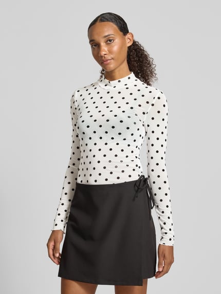 Frauenmodel trägt Slim Fit Langarmshirt mit Allover-Muster Modell 'JESHI' von PIECES, schwarz-weiß, Ganzkörperansicht von vorne.