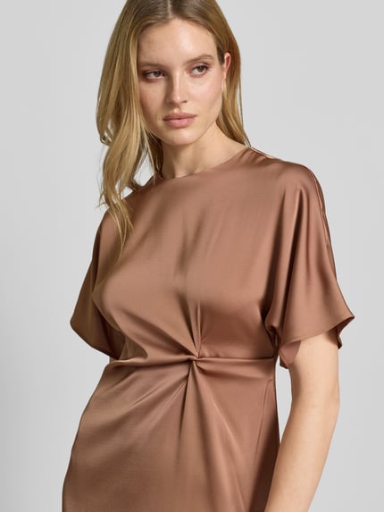 Vrouwenmodel draagt midi-jurk met knoopdetail model 'Dela' van JOOP!, satijn, recht model, ronde hals, detailopname bovenlichaam.