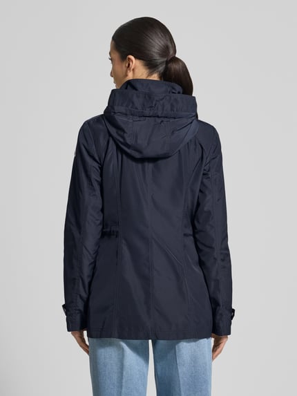 Frauenmodel trägt Regular Fit Jacke mit Logo-Print von Fuchs Schmitt, dunkelblau, Kapuze, Stehkragen, glatte Textur, Ganzkörperansicht Rückansicht.