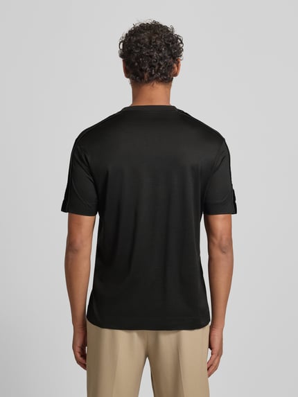 Männermodel trägt T-Shirt mit Label-Detail von Emporio Armani in Schwarz, Lyocell-Baumwoll-Mix, Regular-Fit, Rückenlänge 70 cm, Ganzkörperansicht Rückansicht.