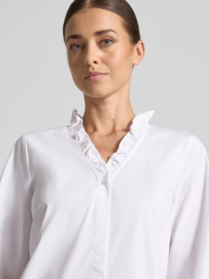 Modelka kobieca nosi Regular Fit Langarmbluse aus Baumwoll-Mix od MORE, biała, stójka z obszyciem falbanami, dekolt w serek, plisa, bufiaste rękawy, mieszanka bawełny i elastanu, Nahaufnahme górnej części ciała.